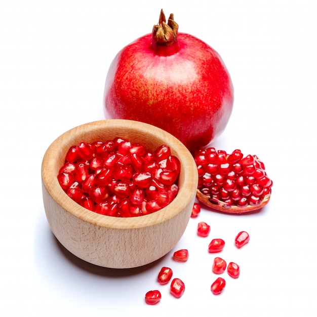 Pomegranate and seeds in wooden bowl