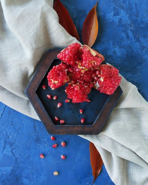 Pomegranate slices on hexagon rustic tray and blue background