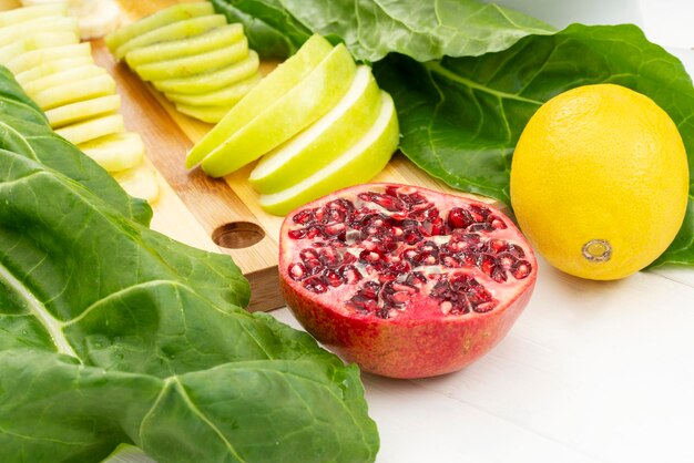 A pomegranate with lemon fruit and spinach on a kitchen cutting board