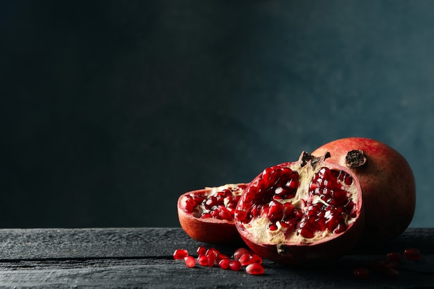 Pomegranate on wooden table, space for text. Juicy fruit