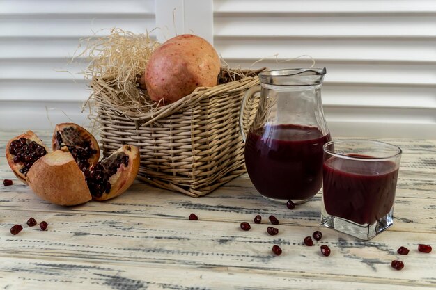 Pomegranates in a basket and on the table on a wooden background Pomegranate juice