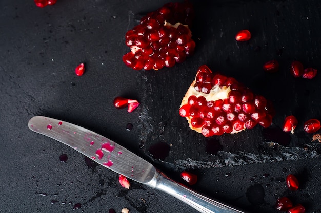 Pomegranates and pomegranate seeds on a dark background