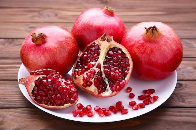 Pomegranates on white plate on a brown background