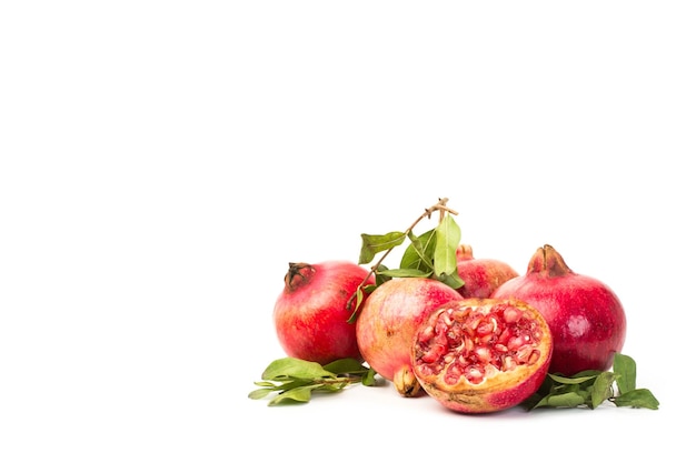 Pomegranates with branches and leaves on a white background with copy space