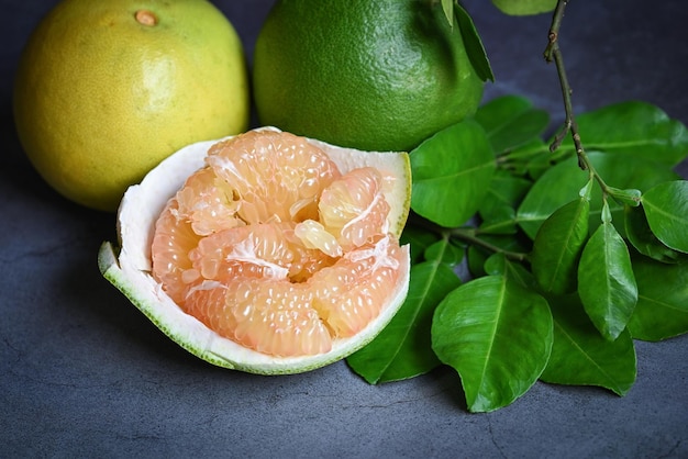 Photo pomelo fruit and dark background fresh green pomelo peeled on plate and green leaf frome pomelo tree pummelo grapefruit in summer tropical fruit in thailand