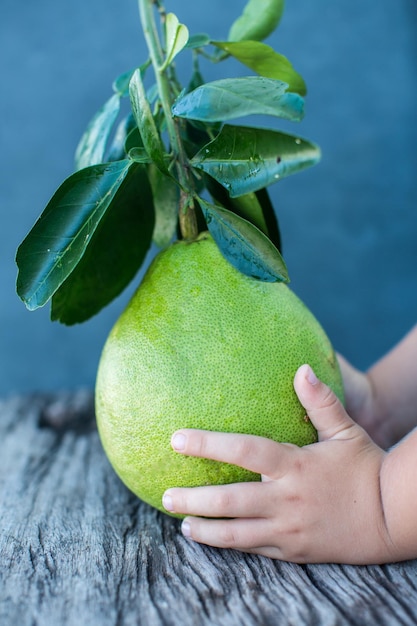 Pomelo with green leaves on a wooden board