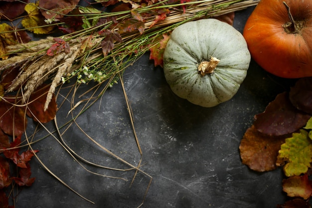 Pompoen en herfstbladeren op donkere tafel