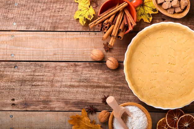 Pompoen en voedselingrediënten, kruiden, kaneel en keukengerei op oude rustieke houten achtergrond. Concept zelfgemaakte bakken voor vakantie. Pompoentaart en koekjes koken voor Thanksgiving day.