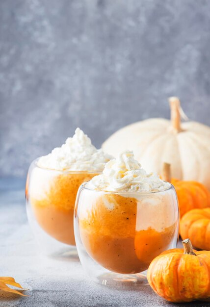 Pompoen gekruide latte of koffie in dubbele glazen beker op grijze tafel Herfst of winter warme drank in feestelijke oranje tafelsetting