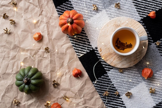 Pompoen met een kopje thee op een geruite ruit herfst oktober decor plat gelegd