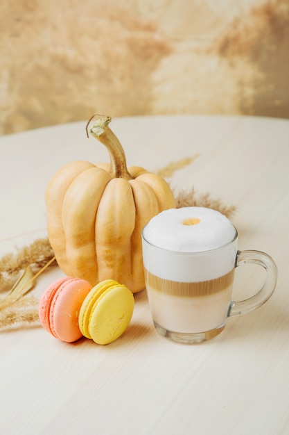 Pompoen Spice Latte. Kopje latte met pompoen, bitterkoekjes en herfstdecor. Traditionele herfstkoffiedrank met koekjes.