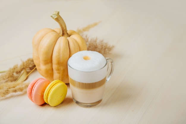 Pompoen Spice Latte. Kopje latte met pompoen, bitterkoekjes en herfstdecor. Traditionele herfstkoffiedrank met koekjes.