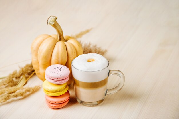 Pompoen Spice Latte. Kopje latte met pompoen, bitterkoekjes en herfstdecor. Traditionele herfstkoffiedrank met koekjes.