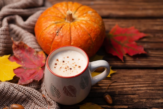 Pompoencappuccino op een houten tafel met herfstdecor