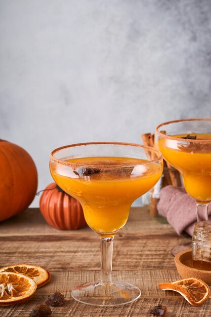 Pompoencocktail met kaneel, sinaasappelsap en cacao in glazen mokken. feestelijke cocktail halloween margarita. pompoen herfstdrankje voor halloween of thanksgiving.