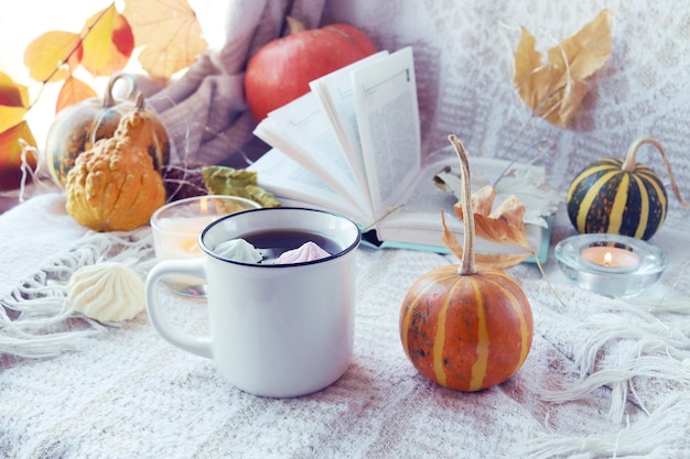 Pompoenen een kopje koffie herfstbladeren brandende kaarsen en een open boek