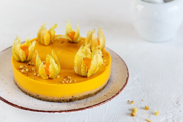 Pompoenkaastaart met physalis op een witte plaat