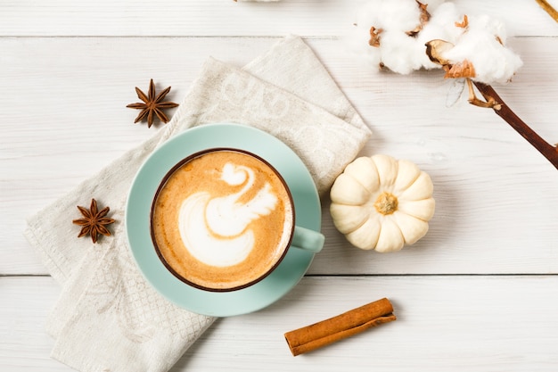 Pompoenkruid latte. Blauwe koffiekop met romig schuim, pijpjes kaneel, anijsplant en kleine gele pompoenen. Herfst herfst warme dranken, café en bar concept, bovenaanzicht