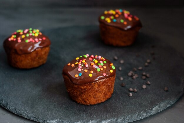 Pompoenmuffins giet chocoladeganache, versier met gekleurde gebakjes