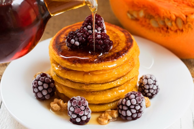 Pompoenpannenkoekjes met ahornsiroop, bessen en noten. einde seizoens (herfst)ontbijt.