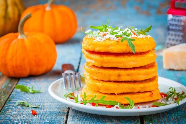 Pompoenpannenkoekjes met chilipeper, Parmezaanse kaas en rucola op rustieke achtergrond