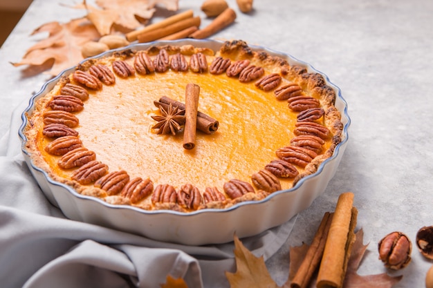 Pompoenpastei en plak met pecannootnoot en kaneel op grijze concrete achtergrond, hoogste mening, exemplaarruimte. Zelfgemaakte herfstgebak voor Thanksgiving