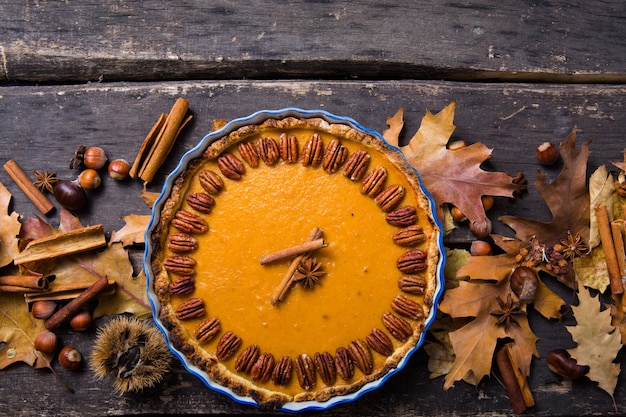 Pompoenpastei met pecannootnoot en kaneel op rustieke achtergrond, hoogste mening, exemplaarruimte. Zelfgemaakte herfstgebak voor Thanksgiving