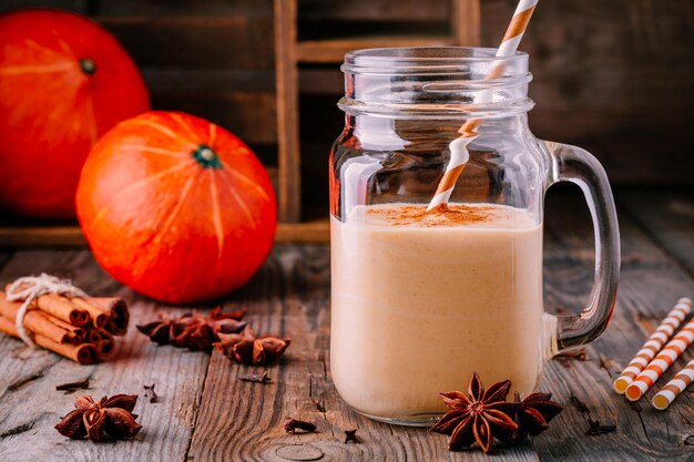 Pompoenpastei smoothie met kaneel in metselaarkruik op houten rustieke achtergrond