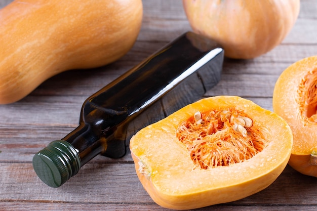 Pompoenpitolie in een glazen pot en verse rauwe pampkin op houten tafel. Gezond eten, dieet of veganistisch voedselconcept.