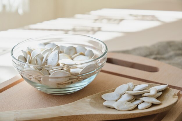 Pompoenpitten in witte kom en lepel op het vlas op de tafel kopieerruimte