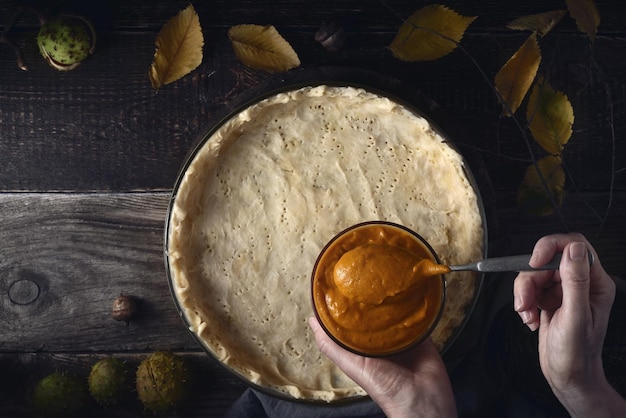 Pompoenpuree op het deeg leggen voor pompoentaart bovenaanzicht