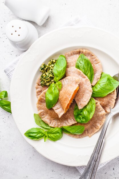 Pompoenravioli met pestosaus in een witte plaat.