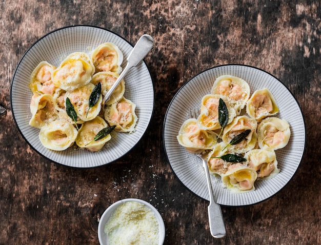 Pompoenravioli met salieboter en Parmezaanse kaas op houten bovenaanzicht als achtergrond