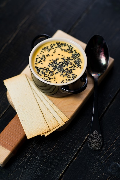 Pompoensoep met zwarte sesam en crackers.