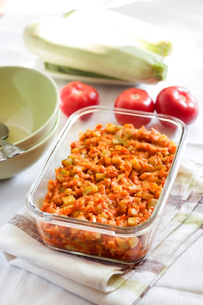 Pompoenstoofpot met wortel en tomaten in een vierkante glazen schaal