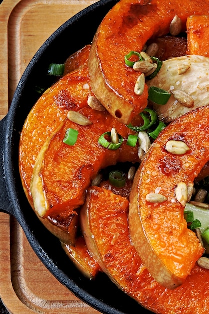 Pompoenstukjes gebakken in een kleine koekenpan met groenten en zaden. Gebakken pompoen. Veganistische lunch met pittig gebakken pompoen. Handige herfstsnack. Halloween lunch.