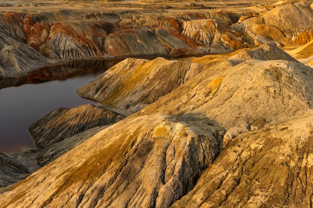 A pond - a lake or a river - with red water in a canyon among deserted sandy hills