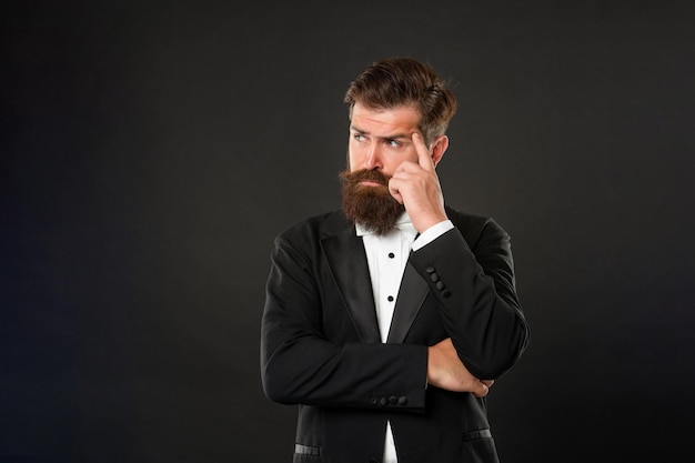 Pondering elegant butler in tuxedo on black background tux