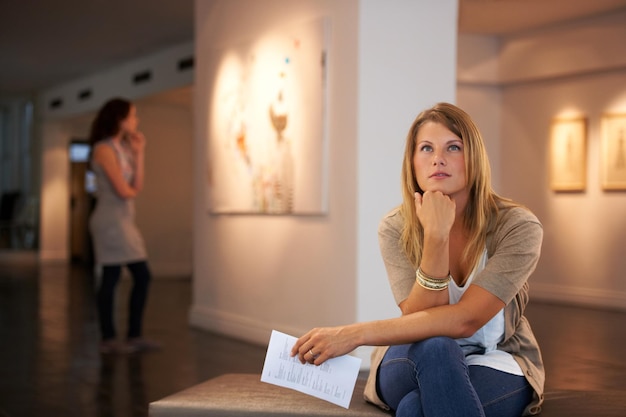 Pondering the paintings themes Two young friends looking at paintings while attending an exhibition