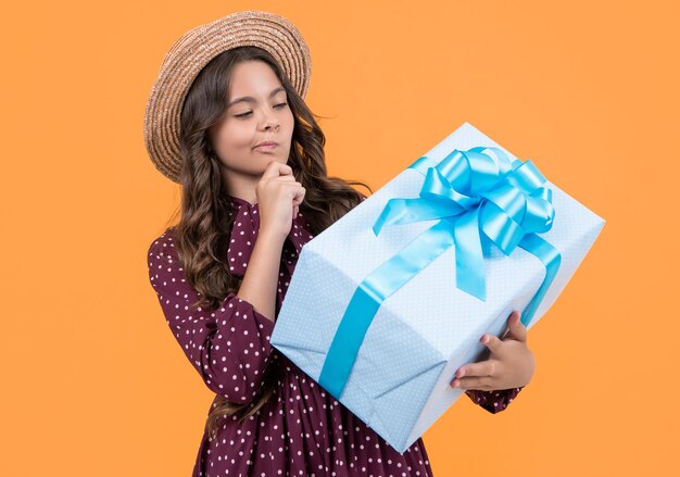 pondering teen girl with present box on yellow background