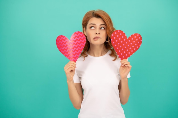 Pondering young woman with red heart on blue background