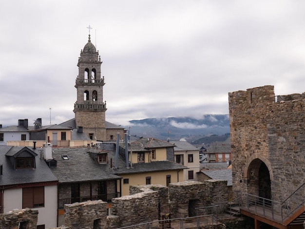 사진 ponferrada leon spain 12122021 바실리카 데 라 엔시나 데 폰페라다(basilica de la encina de ponferrada)의 종탑은 꼭대기에 돔과 십자가가 있는 종을 보여주는 건물들 사이에서 눈에 띕니다.