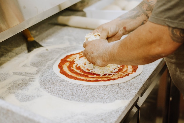 Poniendo tomate en masa de pizza