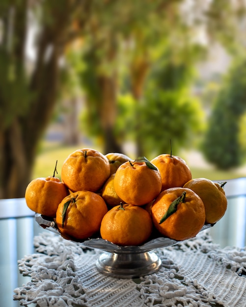 Ponkas tangerines in basket on table and garden in the background.