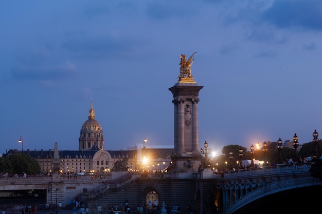 Pont Alexandre III Bridge and illuminated lamp posts at sunset with view of the Invalides 7th Arrondissement Paris France