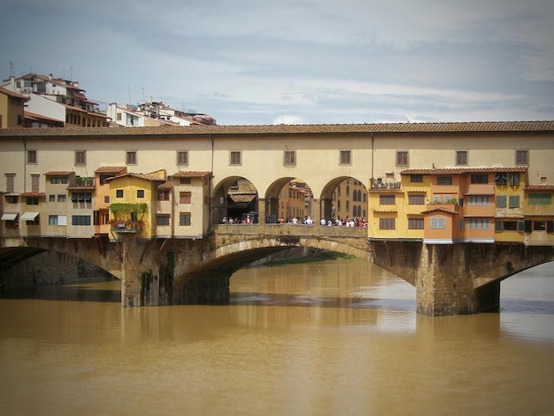 Foto ponte vecchio brug over de rivier door gebouwen tegen de lucht in de stad