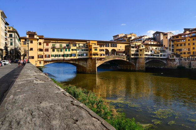 Ponte Vecchio над рекой в городе на фоне голубого неба