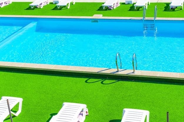 현대적인 레지던스의 수영장 디자인 화창한 날씨의 일광욕 침대 휴가