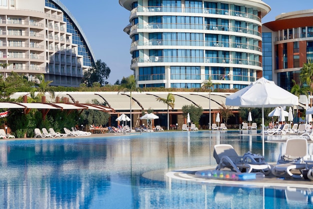 ホテルの背景にある青い水、サンラウンジャー、パラソルのあるプール。ホテルの観光客のための休憩所