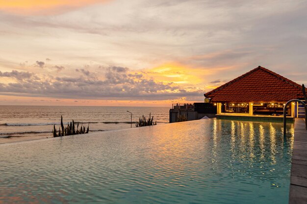 A pool with a house on the side and the ocean in the background